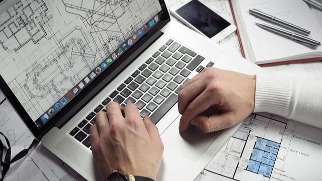 A construction professional reviewing a digital Building Information Modelling model on a laptop at a project site office.