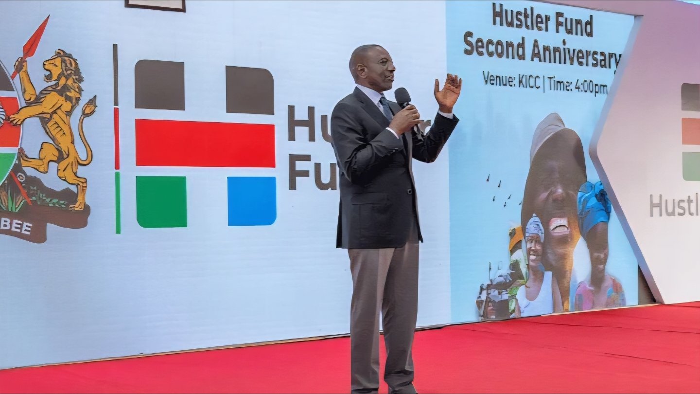 President William Ruto speaking at a podium during the Hustler Fund Second Anniversary event at KICC.