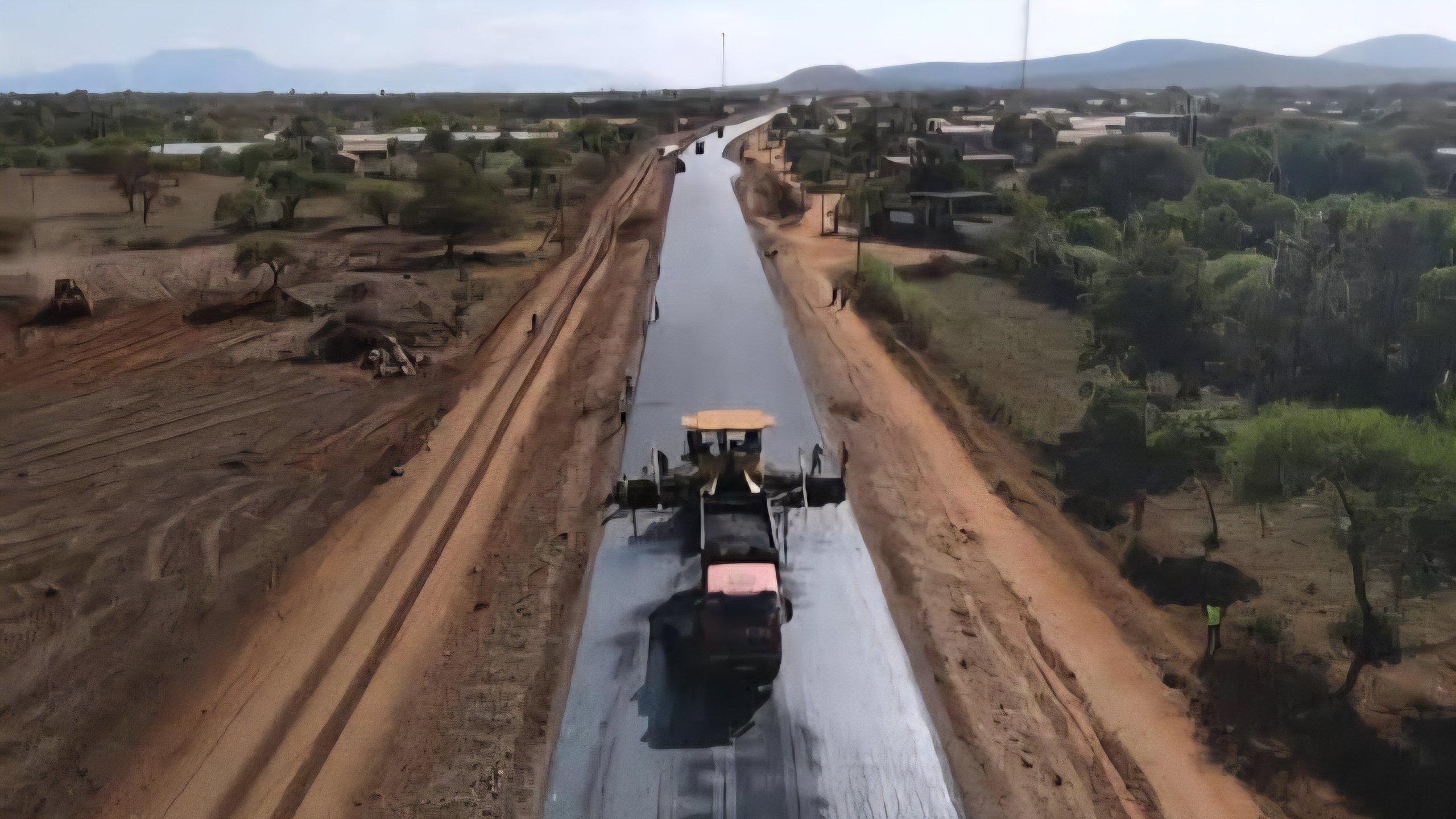 Aerial view of road construction in Taita Taveta County showing a Caterpillar machine grading and improving a rural road surrounded by landscapes.