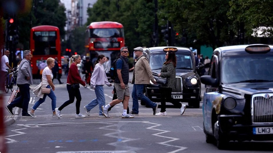 Pedestrians and vehicles cross a busy street in central London amid municipal vehicle emission controls.
