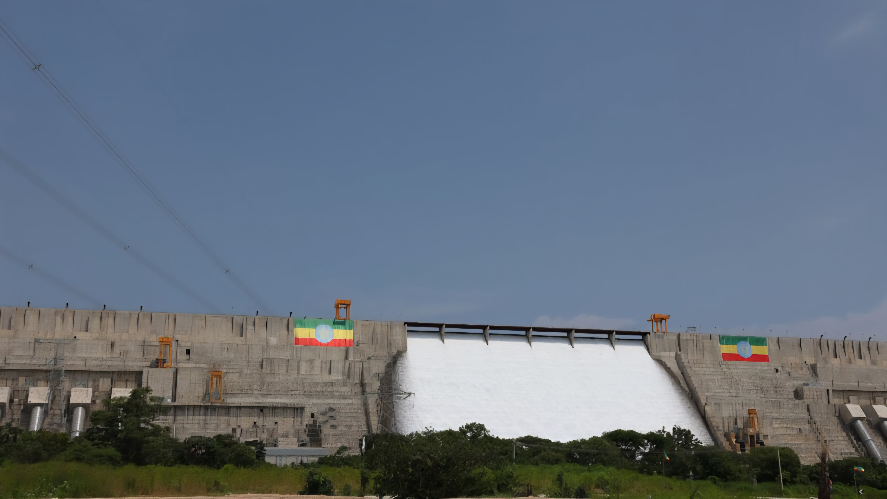 A wide-angle view of the Grand Ethiopian Renaissance Dam (GERD) spillway in Ethiopia, showing water discharging from the massive concrete structure under a clear sky.