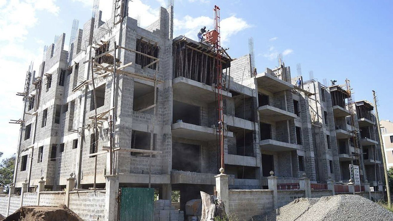 A Nairobi residential development under construction showing incomplete concrete frames and no visible finishing works on upper floors.