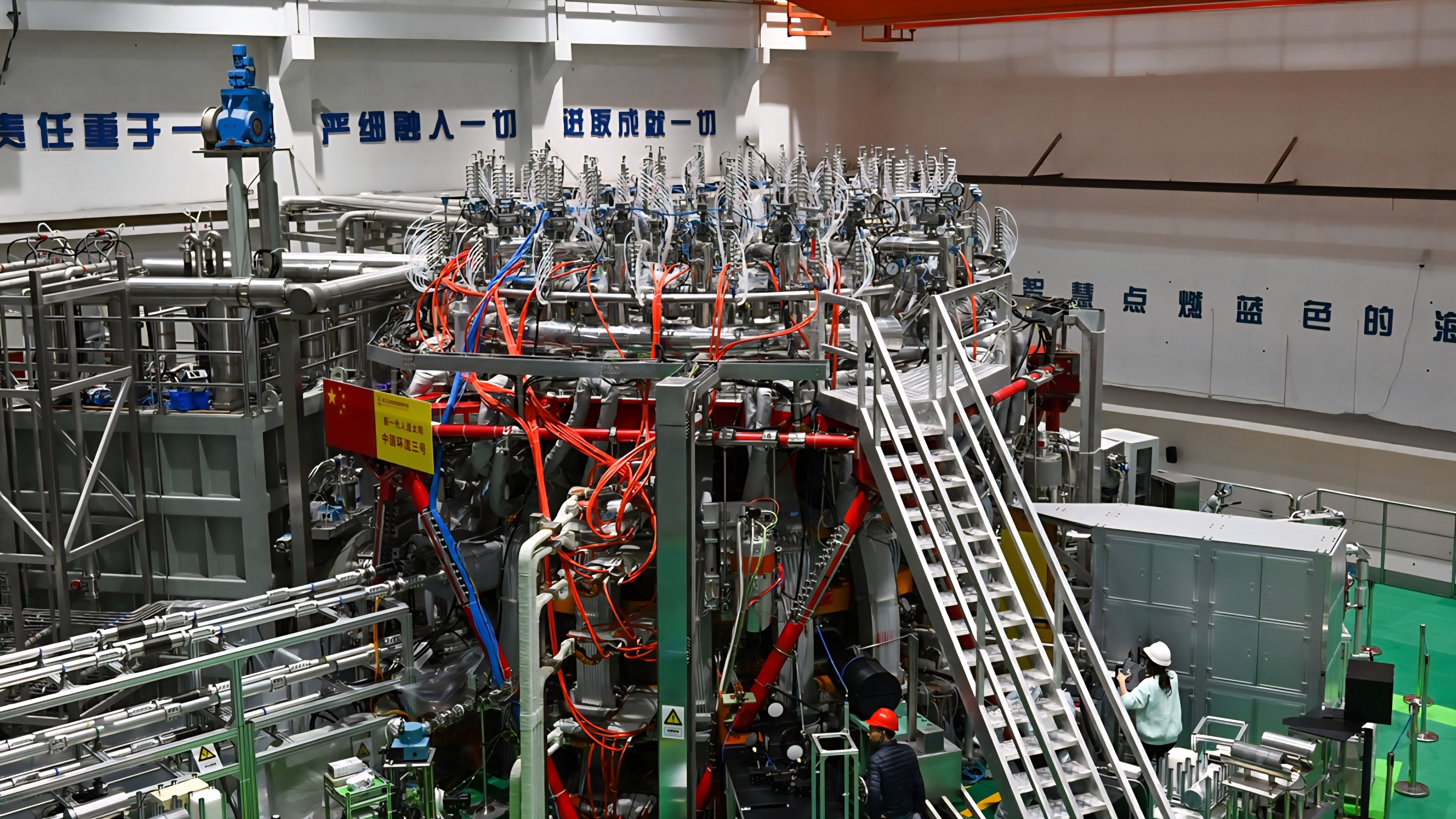 The HL-3 nuclear fusion experimental device at the Southwestern Institute of Physics in Chengdu, showing a complex network of silver piping, wires, and magnetic coils.