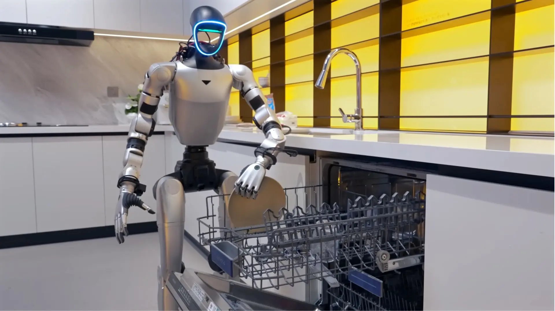 A white humanoid robot standing inside a modern residential kitchen near a countertop and sink.
