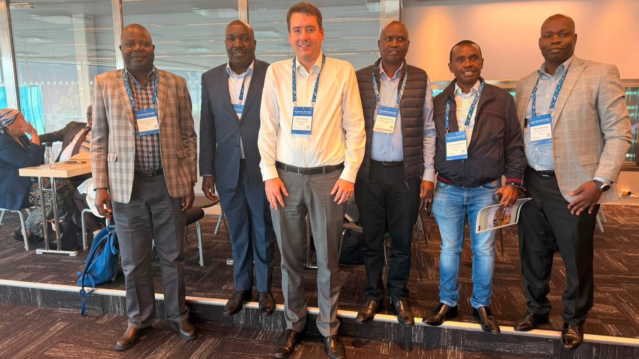 Delegates representing Kenya's Ministry of Water, Sanitation and Irrigation standing together with an international counterpart at a World Water Week conference room in Stockholm.