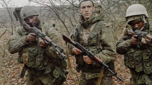 Two Kenyan Defense Force soldiers with a Russian army soldier standing in a forest.