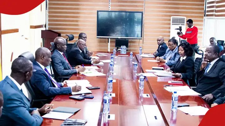 Group of professionals in business suits seated around a long boardroom table during a formal meeting at the KIPPRA offices.
